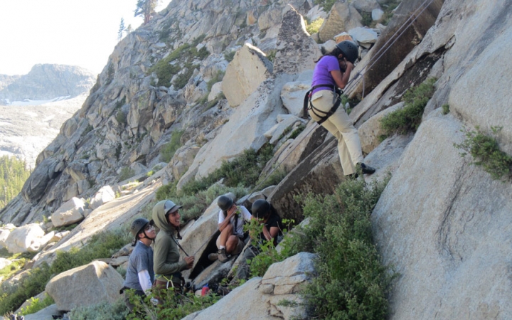 a group of students laugh as they rock climb on an outward bound course for bipoc